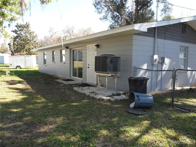 rear view of property with a yard, central AC unit, and fence