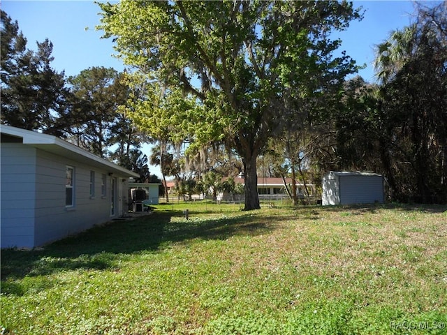 view of yard with an outbuilding, a shed, and fence