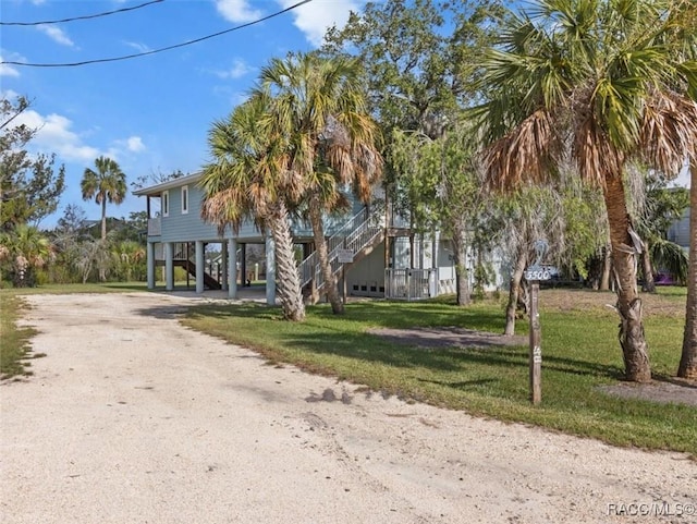 5500 S Cedar Mill Path, Homosassa, FL 34448 - raised beach house featuring a carport, dirt driveway, stairway, and a front lawn