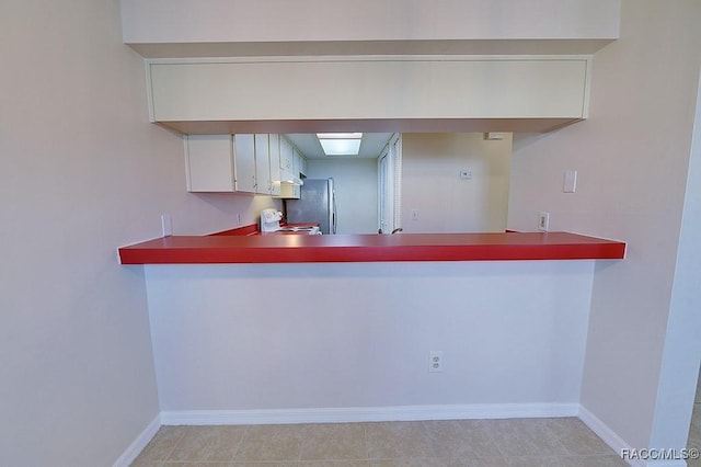 kitchen with white cabinetry, stainless steel fridge, and white range oven