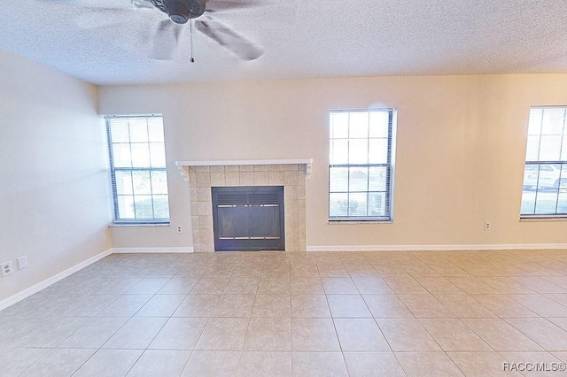 unfurnished living room featuring light tile patterned flooring, ceiling fan, a tiled fireplace, and a textured ceiling