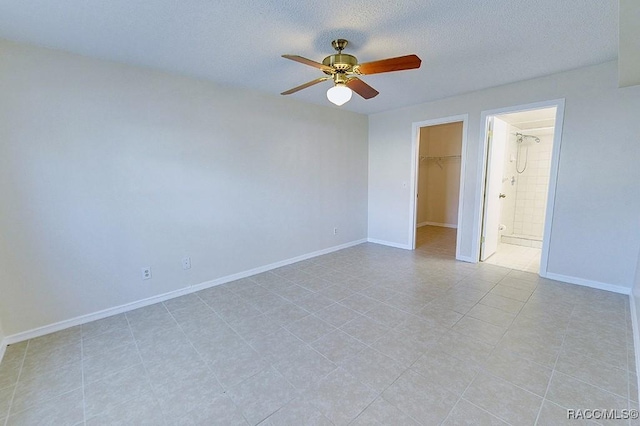 unfurnished bedroom featuring ensuite bath, ceiling fan, a textured ceiling, a walk in closet, and a closet