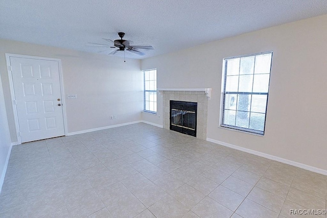 unfurnished living room featuring light tile patterned floors, a textured ceiling, a tile fireplace, and ceiling fan