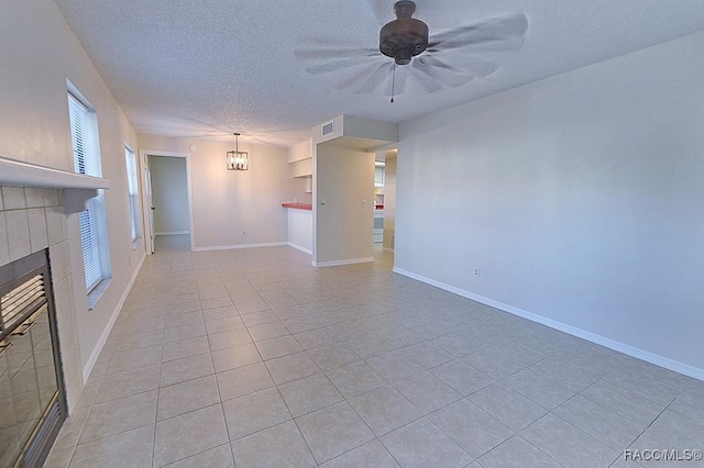 unfurnished living room with a tiled fireplace, ceiling fan with notable chandelier, a textured ceiling, and light tile patterned floors