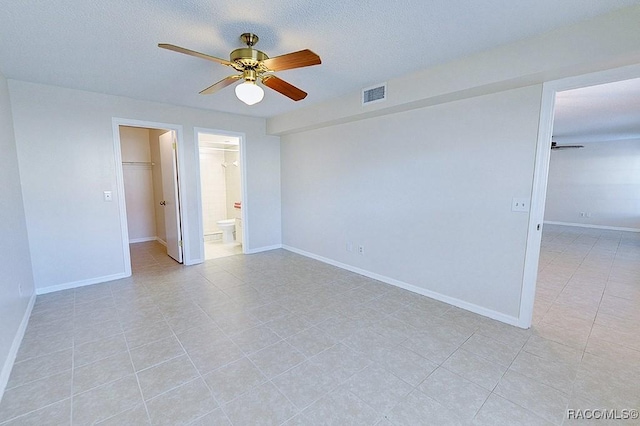 unfurnished bedroom with a spacious closet, a textured ceiling, ceiling fan, and a closet