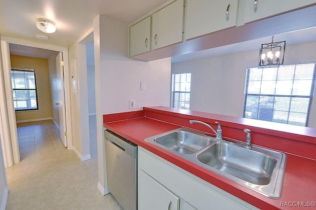 kitchen with light tile patterned flooring, stainless steel dishwasher, sink, and white cabinets