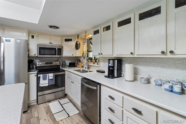 kitchen featuring tasteful backsplash, white cabinets, stainless steel appliances, and light wood-type flooring