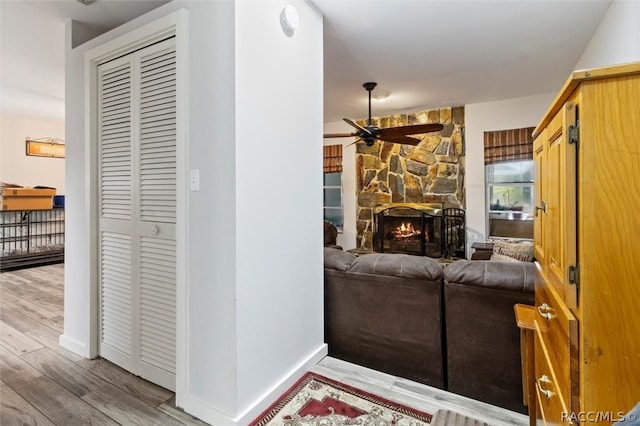 living room featuring ceiling fan, a fireplace, and wood-type flooring