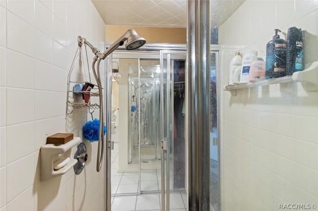 bathroom with tile patterned floors, an enclosed shower, and tile walls