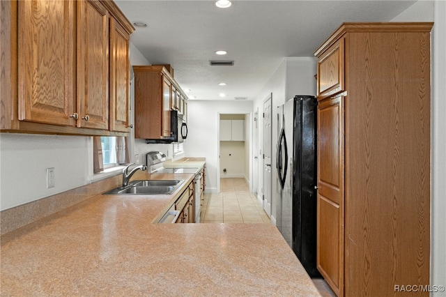 kitchen with black appliances, sink, light tile patterned flooring, and kitchen peninsula