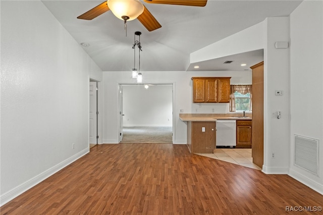 kitchen featuring light hardwood / wood-style floors, ceiling fan, dishwasher, vaulted ceiling, and pendant lighting