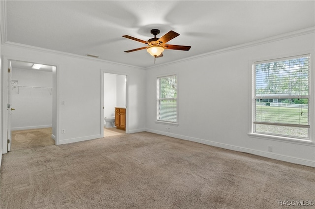 unfurnished bedroom with ceiling fan, a closet, a walk in closet, and ornamental molding