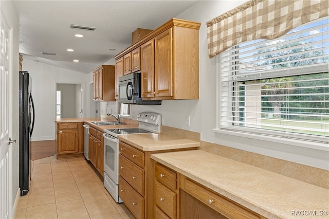 kitchen featuring sink, vaulted ceiling, black appliances, and light tile patterned flooring