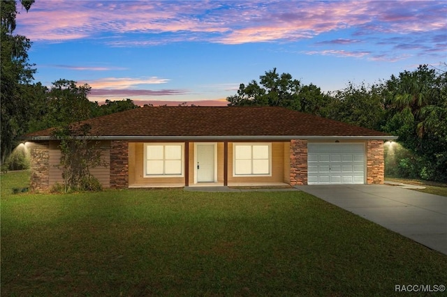 ranch-style home featuring a garage and a yard