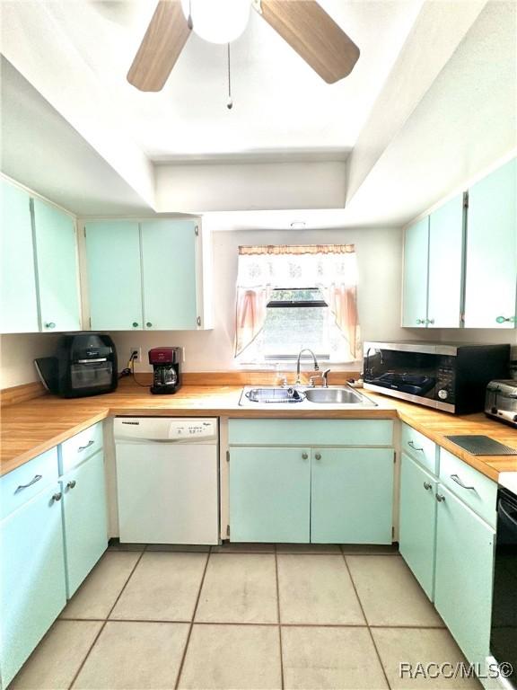 kitchen with a sink, stainless steel microwave, a raised ceiling, and dishwasher