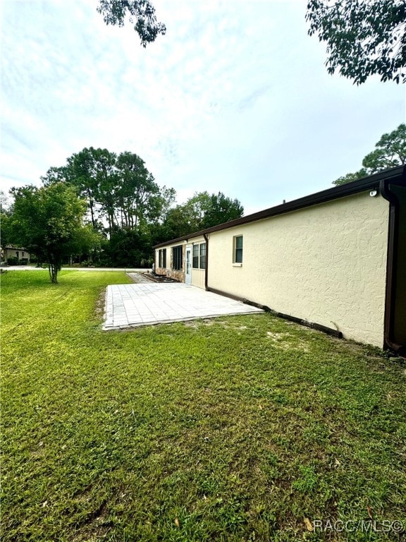 back of property with a yard, a patio area, and stucco siding