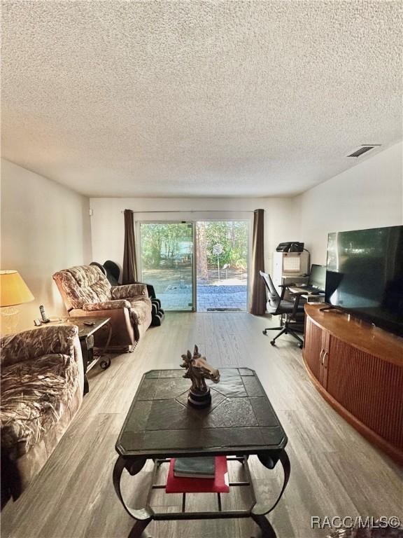 living area featuring visible vents, a textured ceiling, and wood finished floors