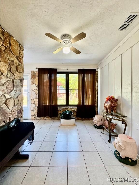 sitting room with light tile patterned floors, ceiling fan, a textured ceiling, and visible vents