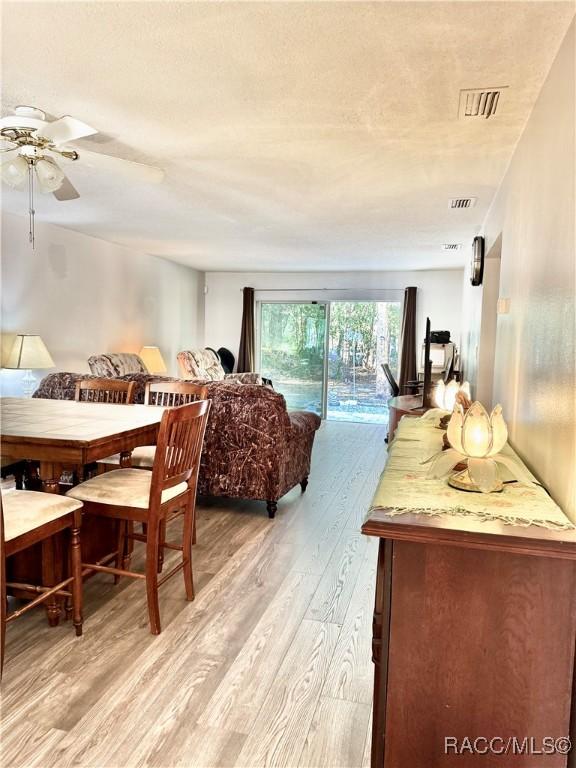 living room featuring ceiling fan, light wood finished floors, and visible vents