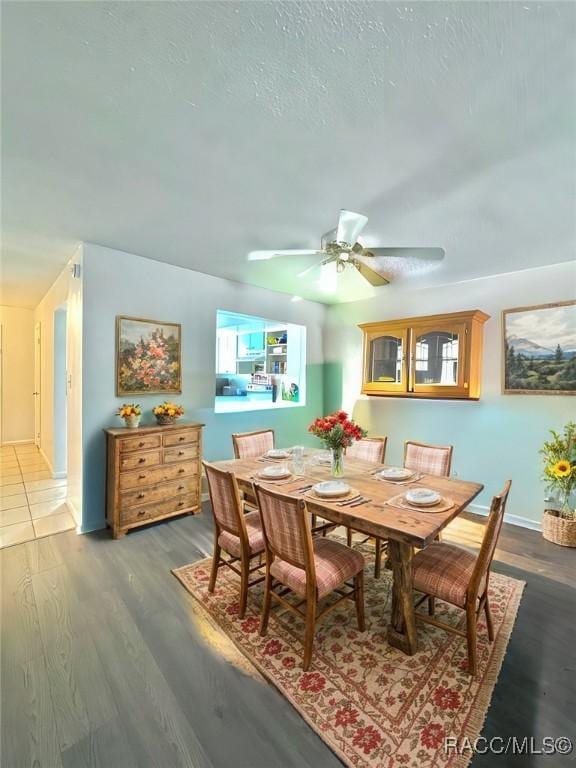 dining space featuring baseboards, a textured ceiling, a ceiling fan, and wood finished floors