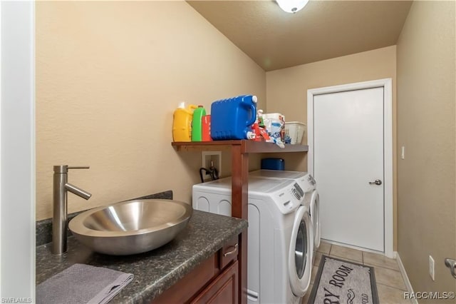 clothes washing area with washing machine and clothes dryer, sink, and light tile patterned floors