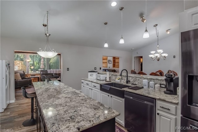 kitchen featuring stainless steel appliances, vaulted ceiling, sink, a center island, and white cabinetry