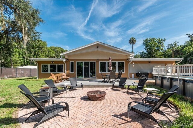 rear view of property with a yard, a patio, and an outdoor fire pit