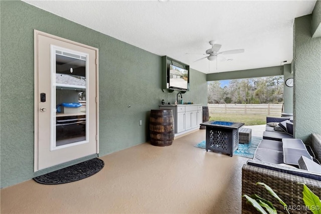 exterior space featuring ceiling fan, sink, and an outdoor living space with a fire pit