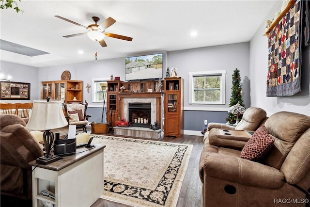 living room featuring hardwood / wood-style flooring, ceiling fan, and a tile fireplace