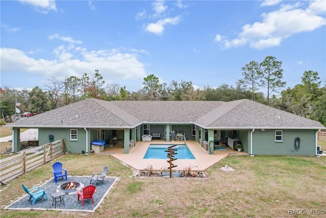 rear view of house with a yard, a fire pit, and a patio