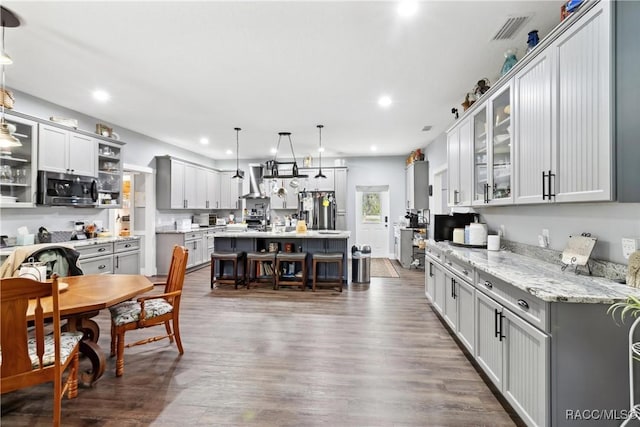 kitchen with a center island, stainless steel appliances, light stone countertops, and hanging light fixtures