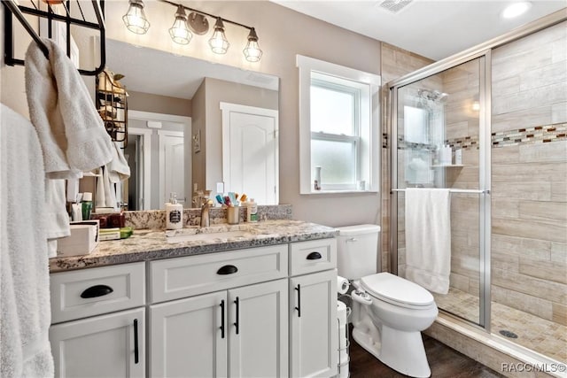 bathroom with vanity, hardwood / wood-style floors, a shower with shower door, and toilet