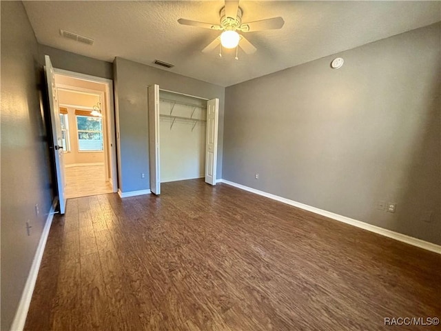 unfurnished bedroom with dark hardwood / wood-style flooring, a closet, and ceiling fan