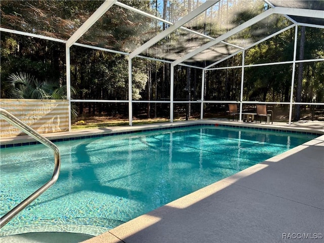 view of swimming pool featuring glass enclosure and a patio