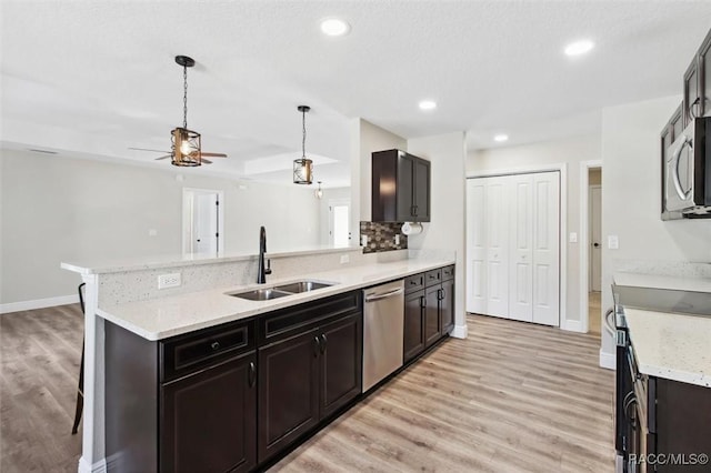 kitchen with a breakfast bar, sink, decorative light fixtures, light hardwood / wood-style flooring, and appliances with stainless steel finishes