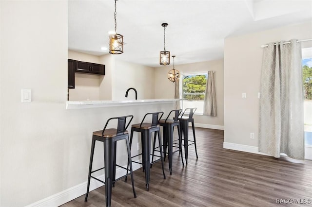 kitchen featuring dark brown cabinetry, dark wood-type flooring, kitchen peninsula, and a breakfast bar