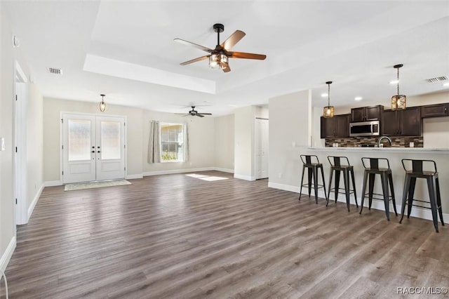 unfurnished living room with french doors, sink, wood-type flooring, a tray ceiling, and ceiling fan