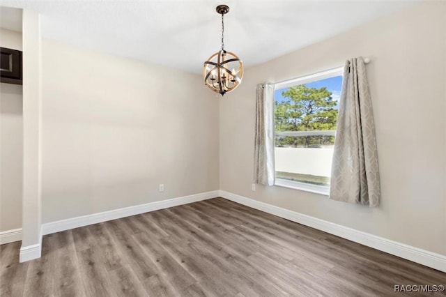 unfurnished room featuring wood-type flooring and a notable chandelier