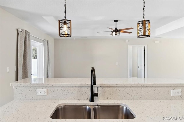 kitchen with hanging light fixtures, sink, and light stone counters