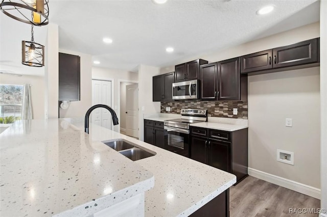 kitchen featuring sink, light stone counters, tasteful backsplash, hanging light fixtures, and stainless steel appliances