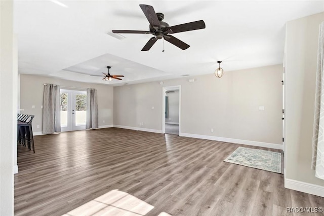 unfurnished living room with french doors, a raised ceiling, and light hardwood / wood-style floors