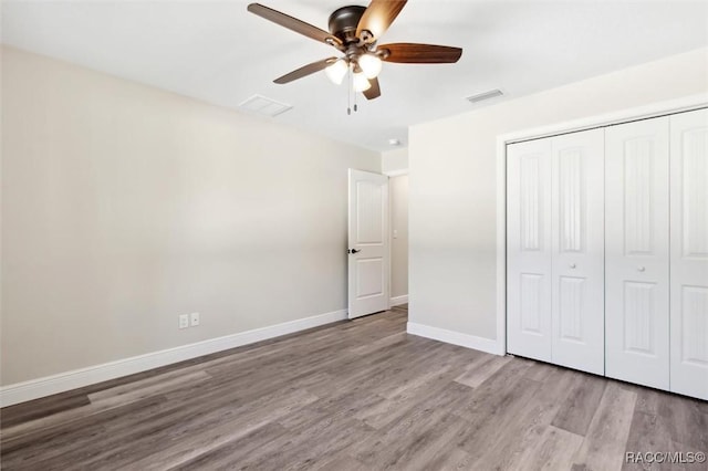 unfurnished bedroom with ceiling fan, a closet, and light wood-type flooring