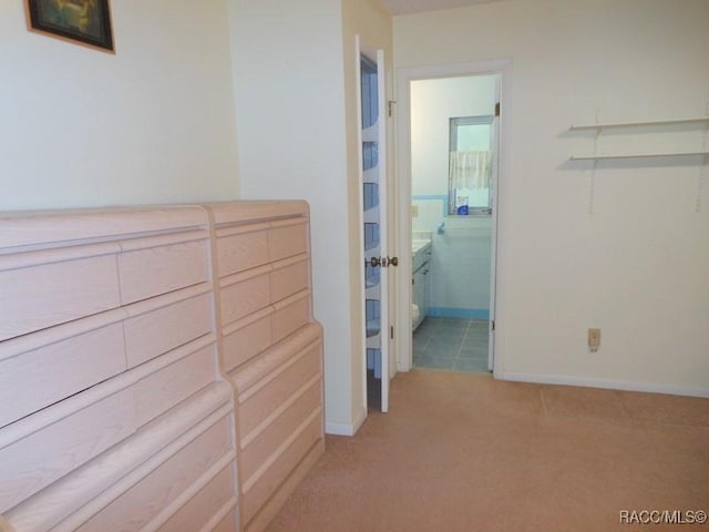 hallway with baseboards and light colored carpet