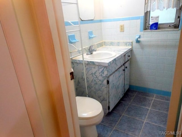 bathroom featuring tile patterned floors, toilet, vanity, and tile walls