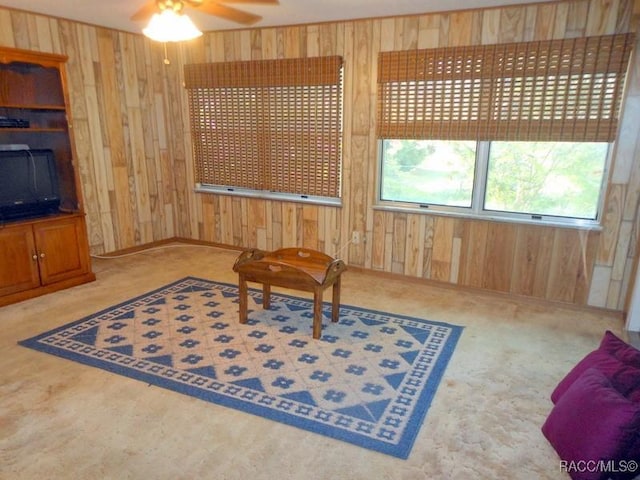 sitting room with wood walls and ceiling fan
