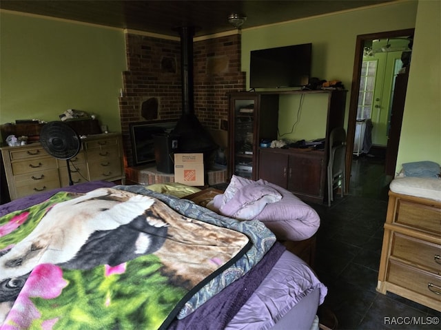 bedroom featuring dark tile patterned flooring, a wood stove, and ornamental molding