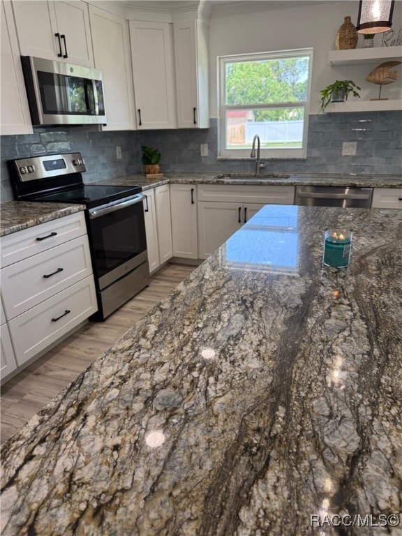 1464 NW 22nd St, Crystal River, FL 34428 - kitchen featuring stainless steel appliances, a sink, light wood-style floors, white cabinetry, and decorative backsplash