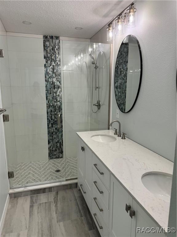 1464 NW 22nd St, Crystal River, FL 34428 - full bath featuring a textured ceiling, a shower stall, double vanity, and wood finished floors