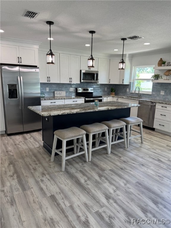 1464 NW 22nd St, Crystal River, FL 34428 - kitchen featuring appliances with stainless steel finishes, a breakfast bar area, white cabinetry, open shelves, and a textured ceiling