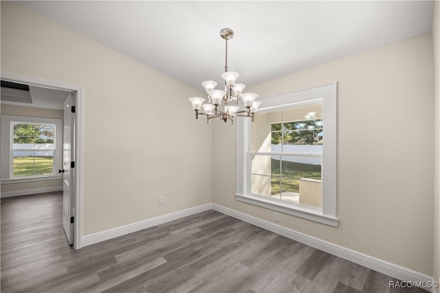 spare room featuring a wealth of natural light, hardwood / wood-style floors, and a notable chandelier